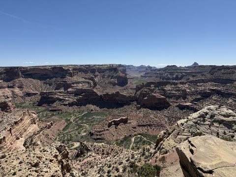 A broad view across the canyon from the rim, its banded walls and side drainages spreading out below a hazy skyline.