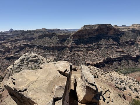Two large fractured boulders perched on the rim, with the canyon and its terraced red walls falling away behind them.