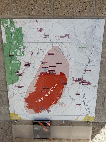 An outdoor map panel on a brick wall titled "The Swell," the San Rafael Swell outlined in red across a map of the surrounding highways and towns.
