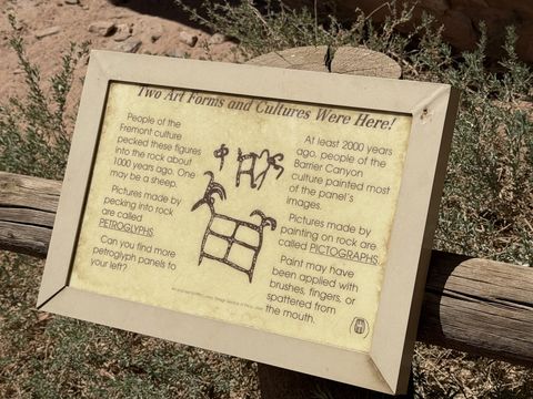 A small framed trailside sign titled "Two Art Forms and Cultures Were Here!" explaining the difference between pecked petroglyphs and painted pictographs.