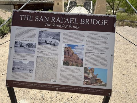 A large interpretive sign titled "The San Rafael Bridge — The Swinging Bridge," with archival photographs and a map, the bridge itself visible behind it.