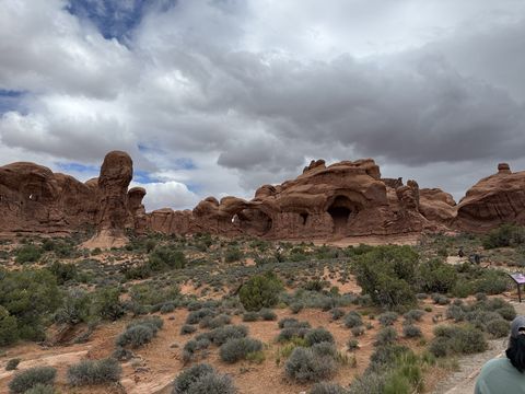 Double Arch in Arches National Park, its two openings side by side in one massive sandstone dome, under a heavy grey overcast.
