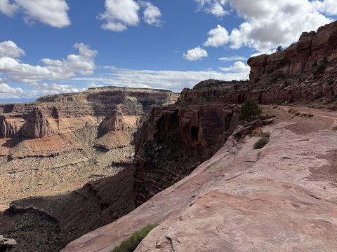 A sloping slickrock rim above Shafer Canyon, the canyon's layered walls curving away to the left.