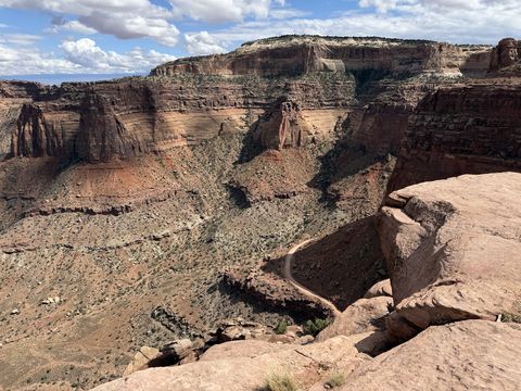 The switchbacks of the Shafer Trail cut into the canyon wall far below the rim, the dirt road doubling back on itself down the cliff.