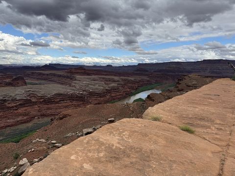 A tilted slab of the White Rim in the foreground, the Colorado River running below it through a wide red canyon.