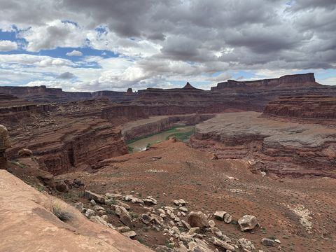 A bend of the Colorado River far below the rim, stepped cliffs on both banks and towers on the distant skyline.