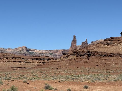 Monster Tower standing tall on the ridge above a banded cliff line, with the lower fin of Washer Woman Arch and its opening just to the right.