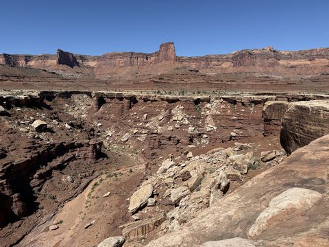 A boulder-strewn rim above a side canyon, with a squat sandstone tower on the mesa across the way.