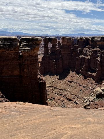 A row of dark, weathered pinnacles below the rim of Monument Basin, distant mountains faint on the horizon.