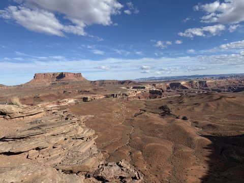 A flat-topped butte above rolling desert benches, the White Rim slickrock in the foreground.